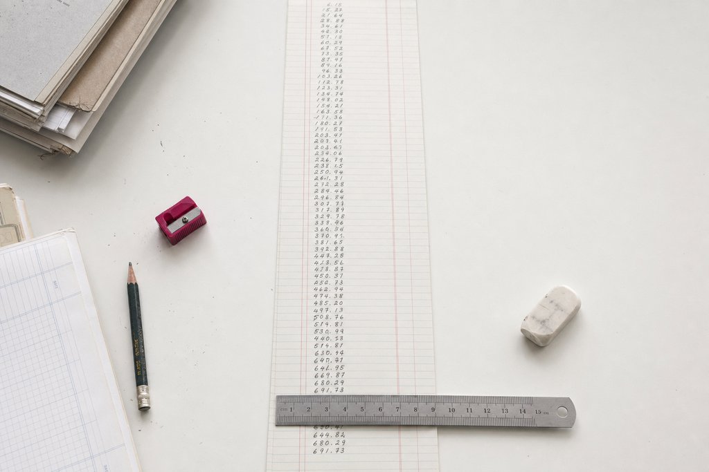 A strip of ruled ledger paper with a lengthening column of handwritten figures