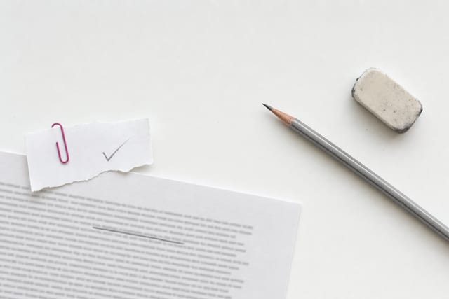 A printed terms sheet with one clause underlined in pencil, a torn slip of paper clipped on top