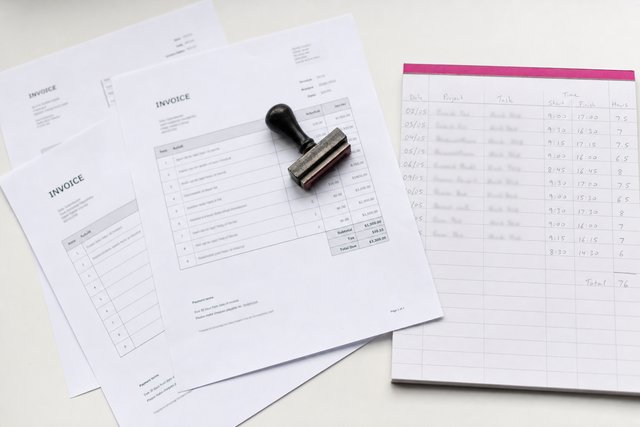Three printed invoices at slight angles beside a ruled timesheet filled in by hand