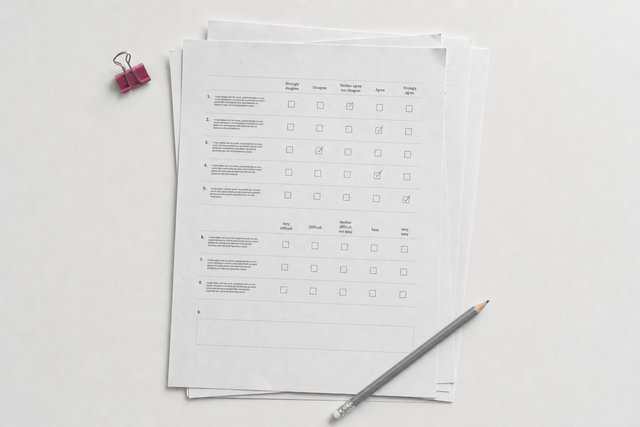 Printed paper questionnaires stacked slightly out of alignment, the top one part-completed